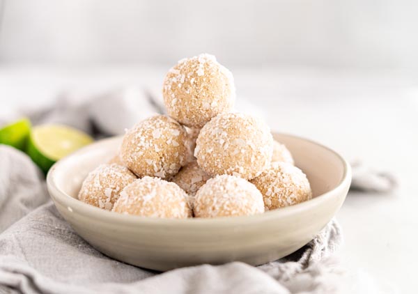 a bowl with coconut lime balls stacked on top of each other