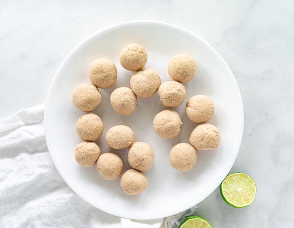 a bunch of balls on a plate with a bowl of coconut next to it