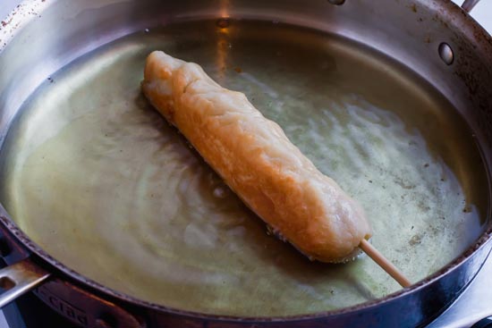 keto corn dog simmering in oil