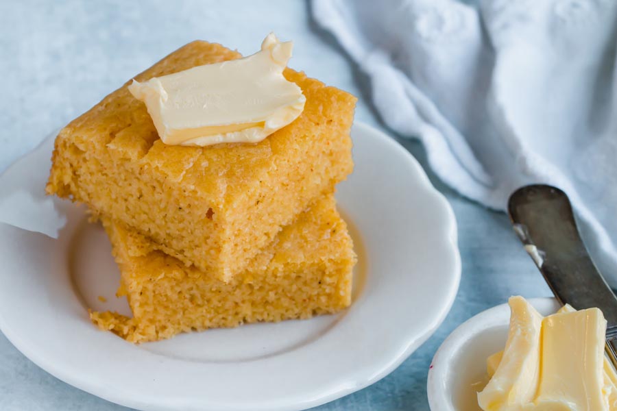 spreading butter on a slice of low carb cornbread