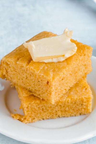 Two slices of low carb cornbread on a side plate with butter.