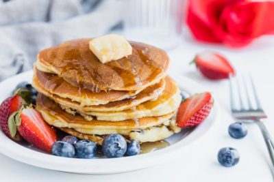 a stack of keto pancakes with blueberries and strawberries near