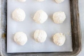 six balls of cheesecake on a parchment lined baking tray