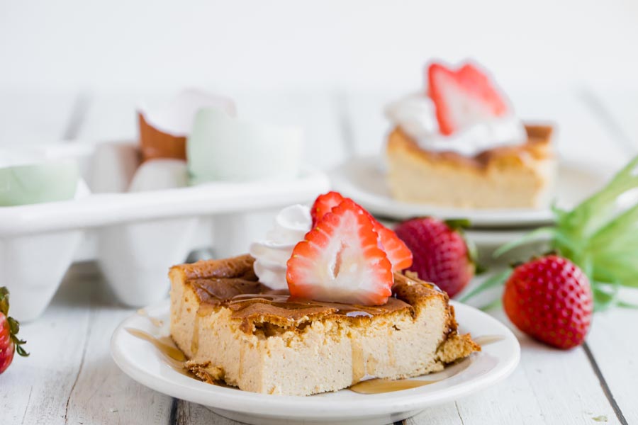 a slice of french toast bake topped with strawberries and syrup