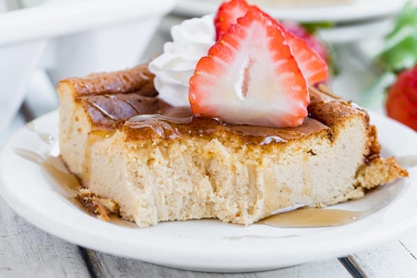 a bite of casserole taken out of french toast with a strawberry slice on top