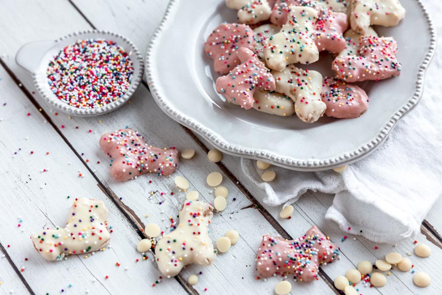 a side dish of rainbow sprinkles next to pink and white sugar free animal cookies