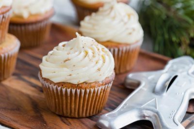 multiple muffins frosted with cream frosting and a gingerbread man cookie cutter nearby