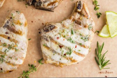 bone in pork chop with grill marks on a cutting board with a butter glaze on top