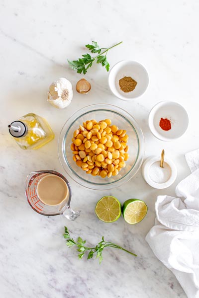 Ingredients for hummus in bowls surrounding a large bowl of lupini beans in the center.