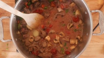 hearty beef stew mixed with a wooden spatula