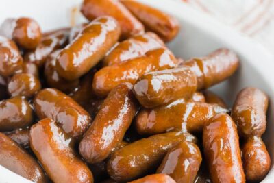 A pile of sauce covered little smokies sausage in a bowl.