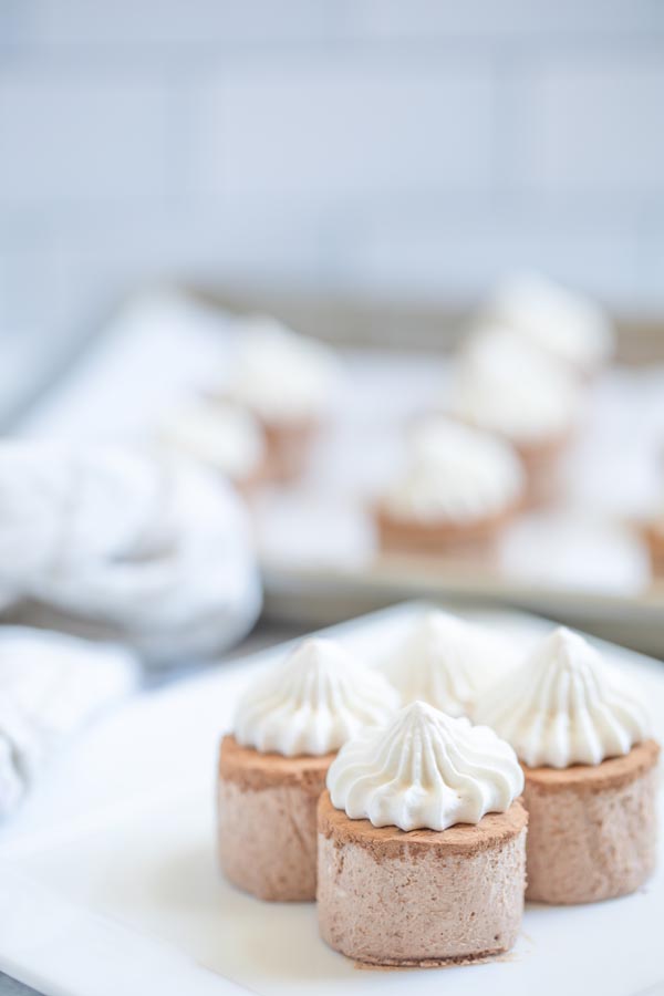 a couple of chocolate fat bomb desserts on a plate topped with whipped cream