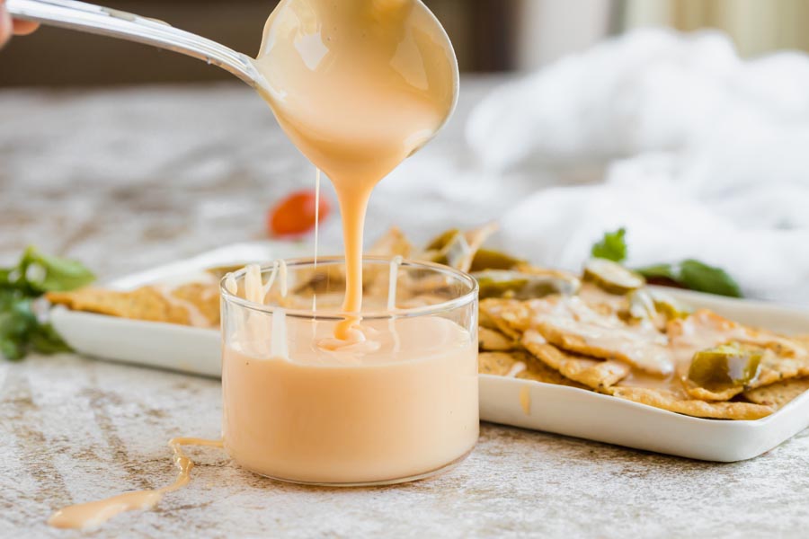 a spoonful of dripping queso into a bowl