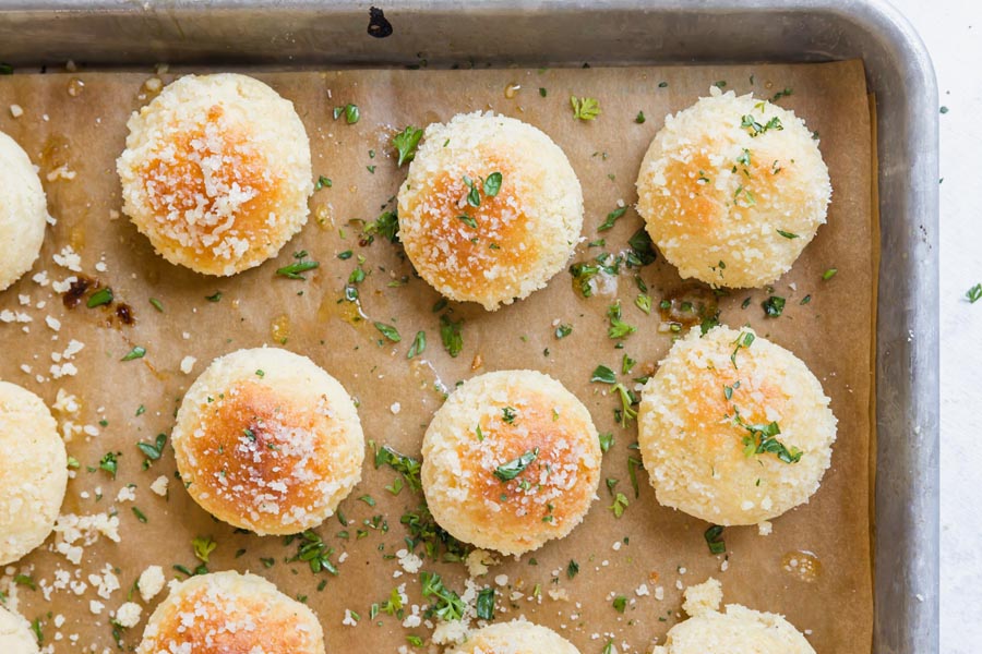 looking down onto golden rolls with parmesan and herbs on a tray