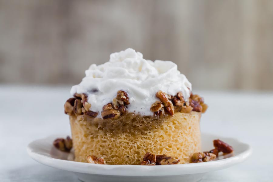 whipped cream topped on a keto pecan pie mug cake