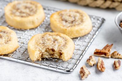 a bite out of a cookie sitting on a wire rack next to crushed pecans