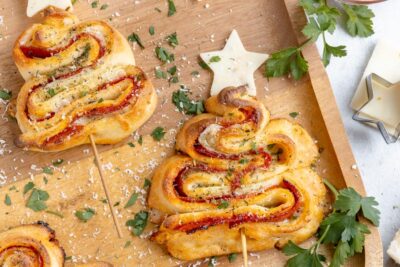 Keto puff pastry christmas trees dusted with parmesan cheese and parsley and topped with a cheese star.