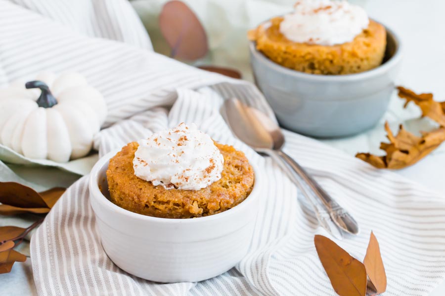 mug cakes for two in a white and grey ramekin on a striped towel with leaves nearby