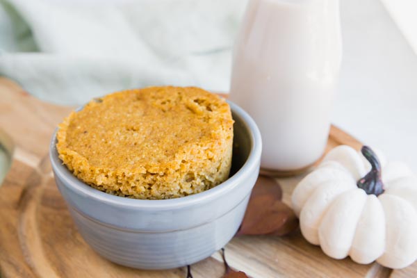 baked pumpkin cake in a grey ramekin next to a glass of milk