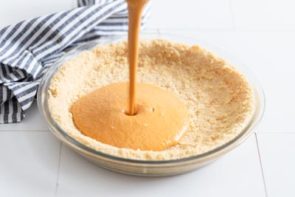 pouring pumpkin pie filling to a pie crust