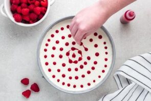 Making heart swirls from raspberry sauce on top of a cheesecake.