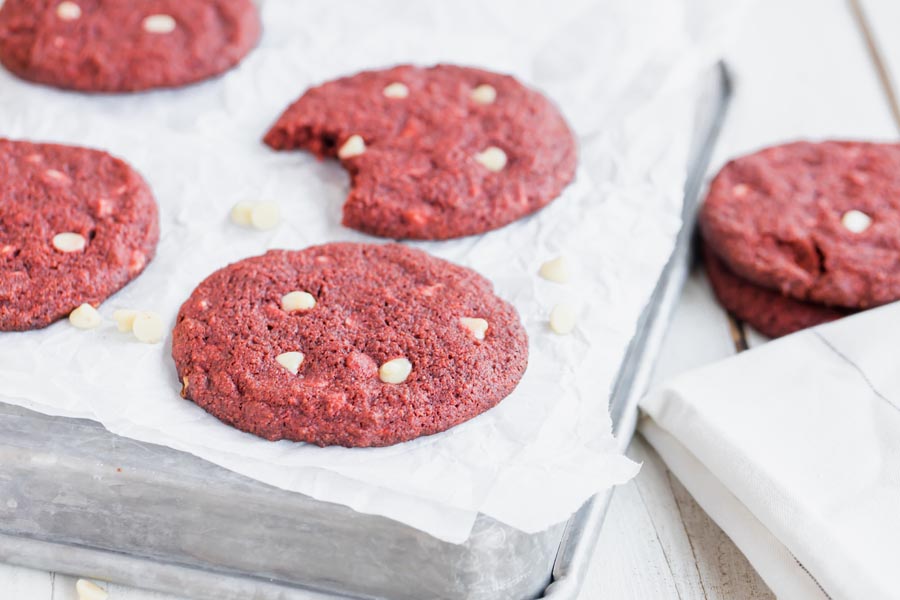 red velvet cookies with white chunks on top of a baking tray