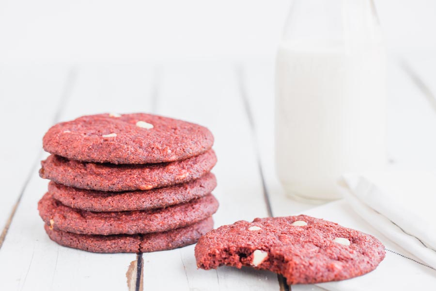 cookies lined in a stack with a half eaten cookie and a jug of milk nearby