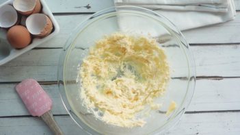 butter creamed in a glass bowl with a spatula next to it