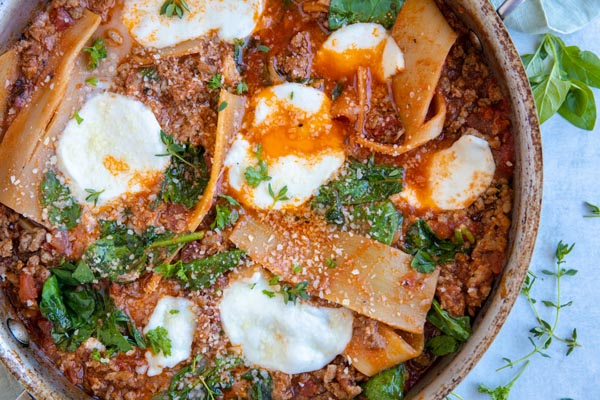 looking down on a skillet full of low carb lasagna topped with spinach and mozzarella