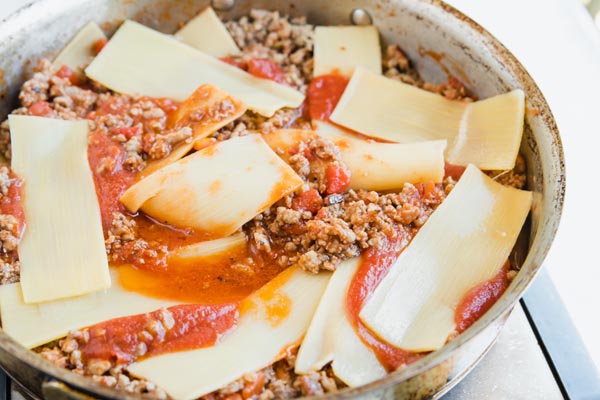 slices of hearts of palm lasagna noodles lying on top of a meaty marinara sauce