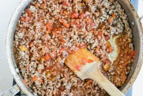 tomato beef sauce in a skillet with a wooden spatula