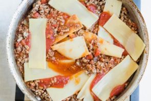 sheets of hearts of palm lasagna noodles on top a skillet with beefy marinara sauce