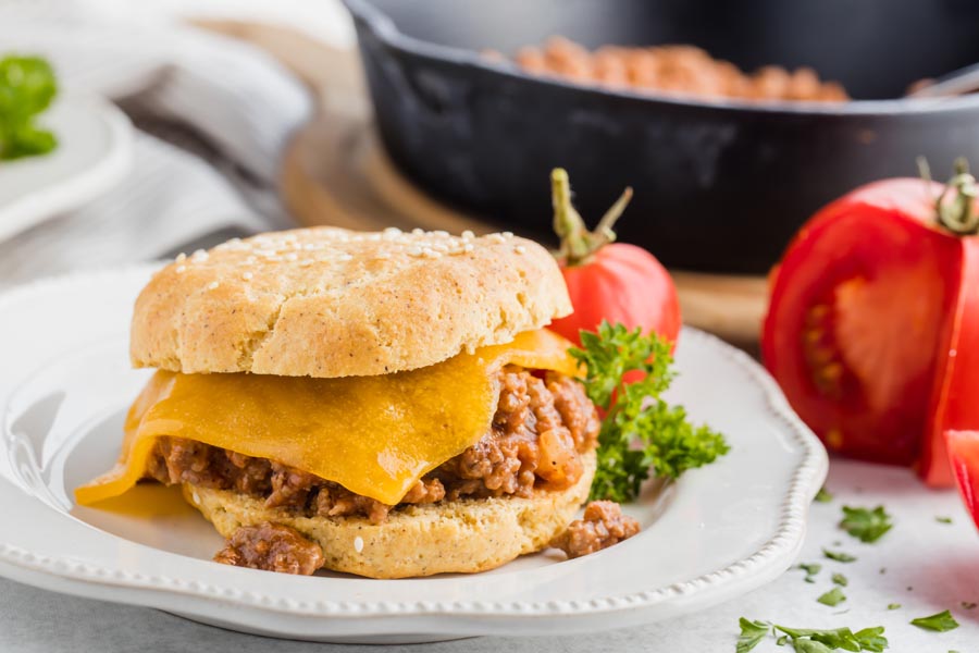 a plate with a sloppy joe burger and tomato on the side