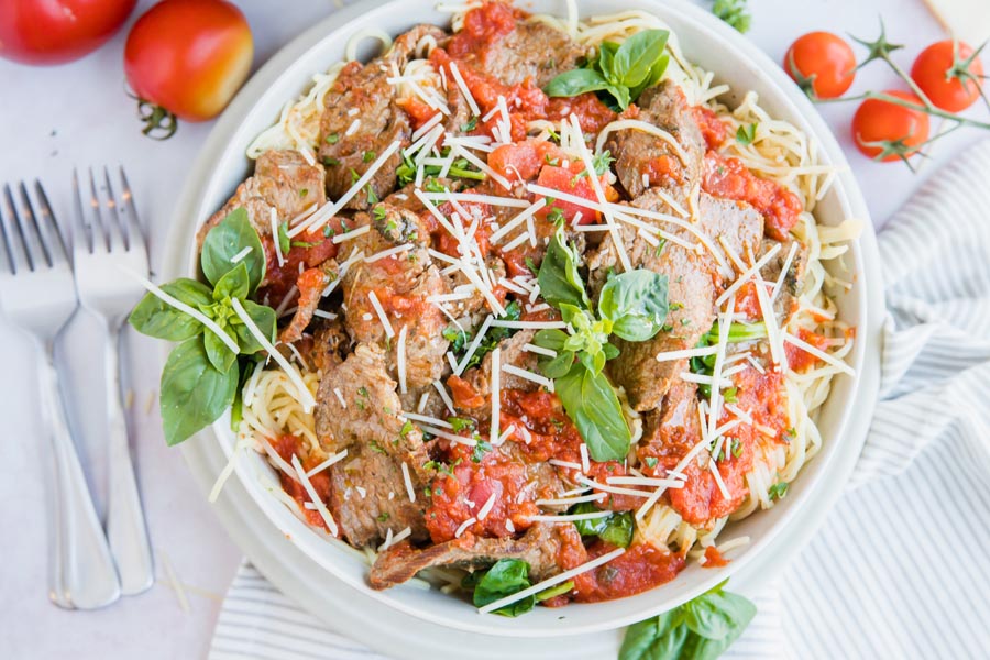 overhead shot of keto marinara sauce with steak slices on noodles topped with parmesan cheese