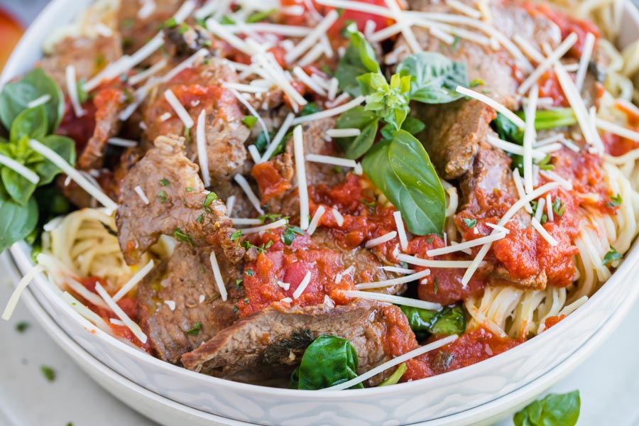 a close up view of sliced steak in maraina sauce over keto pasta