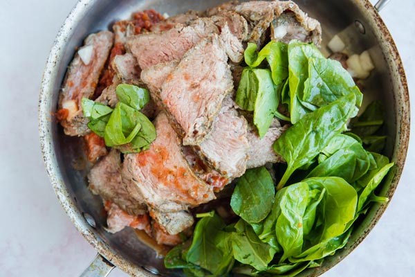 ingredients for steak marinara sauce cooking in a skillet