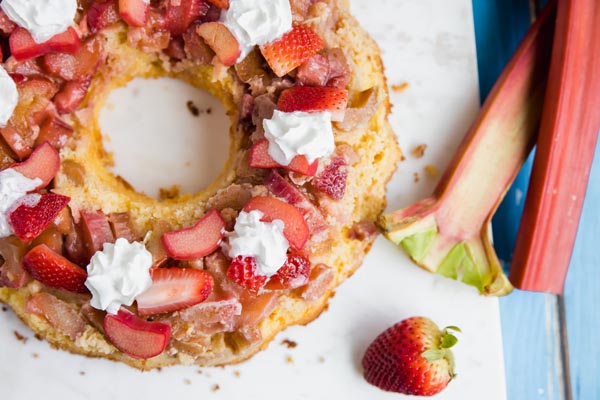 sugar free strawberry rhubarb cake topped with whipped cream next to a rhubarb stalk