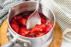 strawberries being stirred in a saucepan with a spoon