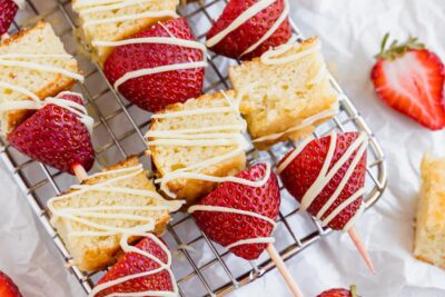 close up of cake and strawberry kebabs with a white icing on top