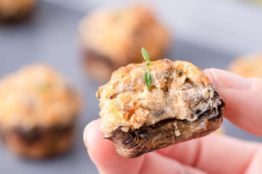 A handing holding a stuffed mushroom with a bite taken out of it.