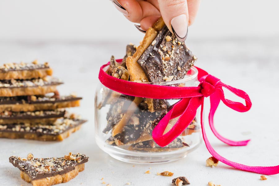 Grabbing a piece of toffee from a dish with a red bow around it.