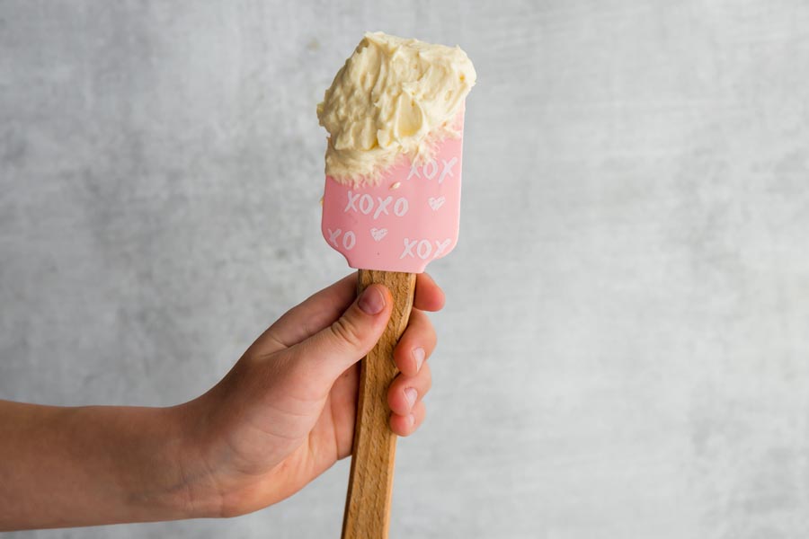 child's hand holding a spatula with keto cream cheese frosting on it