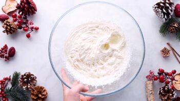 A hand holding a bowl of whipped cream.