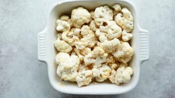 a square baking dish with cauliflower florets