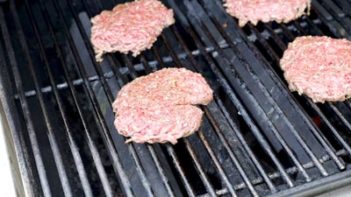 smash burgers cooking on a grill