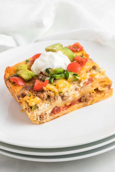 Layers of tortillas mixed with egg and sausage and topped with avocado and tomatoes.