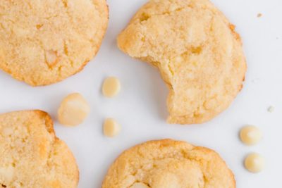 a bite out of a white chocolate cookie with three other cookies near by