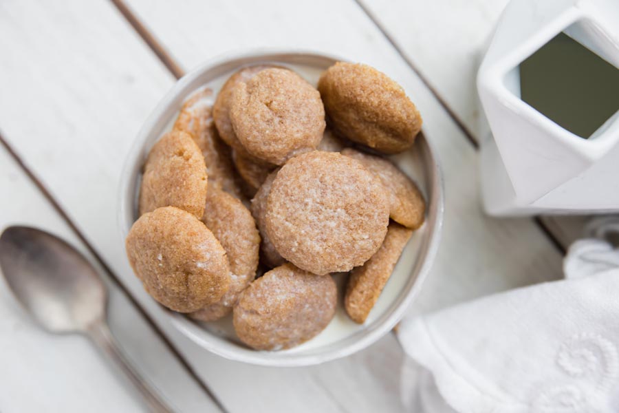 looking into a bowl of mini cookie cereal and nut milk with a spoon nearby