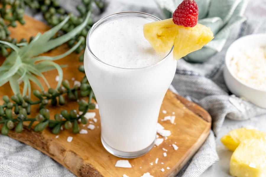 a tropical smoothie with pineapples around and coconut flakes scattered