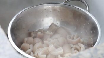 A colander with boiled pork skins inside.